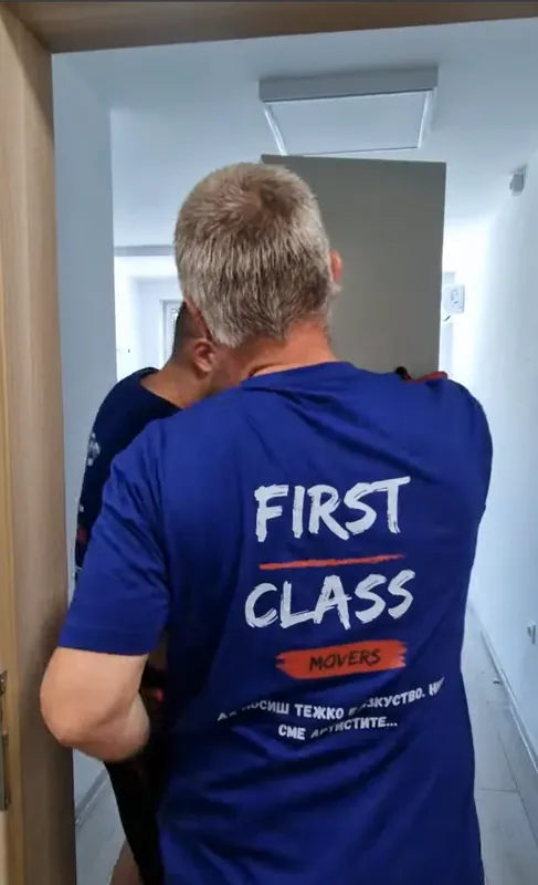 A First Class Movers mover carrying a wardrobe during a home move