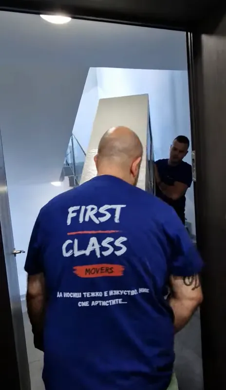 First Class Movers movers carrying furniture into the building entrance